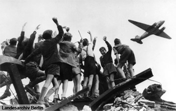 Kinder winken einem Rosinenbomber zu
